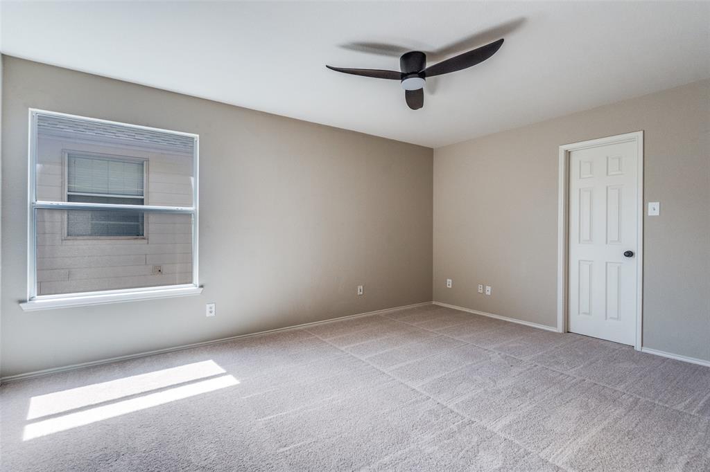 Neutral wall tones, carpeted flooring, multi-pane window, six-panel interior door, and a matte black ceiling fan