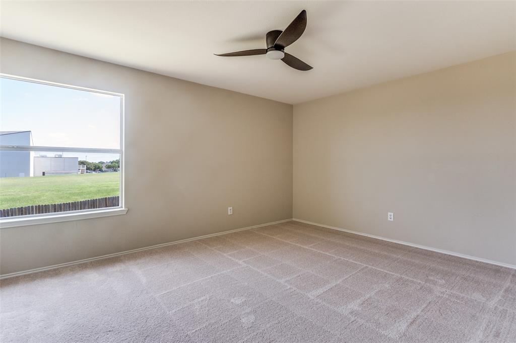 Neutral-toned interior featuring wall-to-wall carpeting, a multi-blade ceiling fan, and a large window with natural light