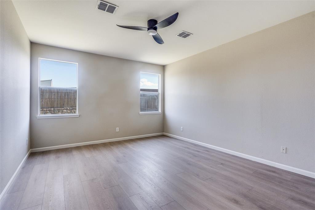 Interior space featuring wood-finish flooring, neutral wall paint, two dual-pane windows, and a matte black ceiling fan