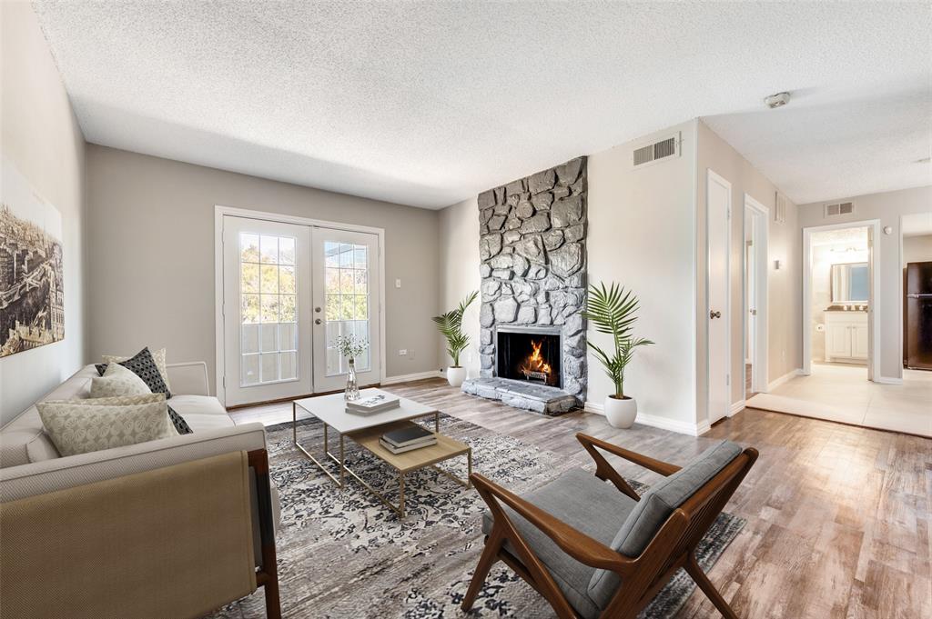 Living room featuring Wood-look luxury vinyl planks (LVP) , a floor-to-ceiling stone fireplace, and French doors