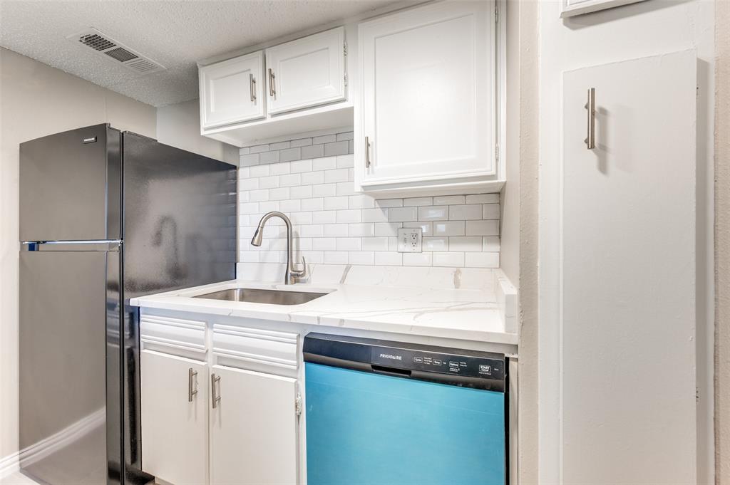 Kitchenette featuring white shaker-style cabinetry, stone-surface countertops, white subway tile backsplash, stainless steel sink with gooseneck faucet, and stainless steel appliances