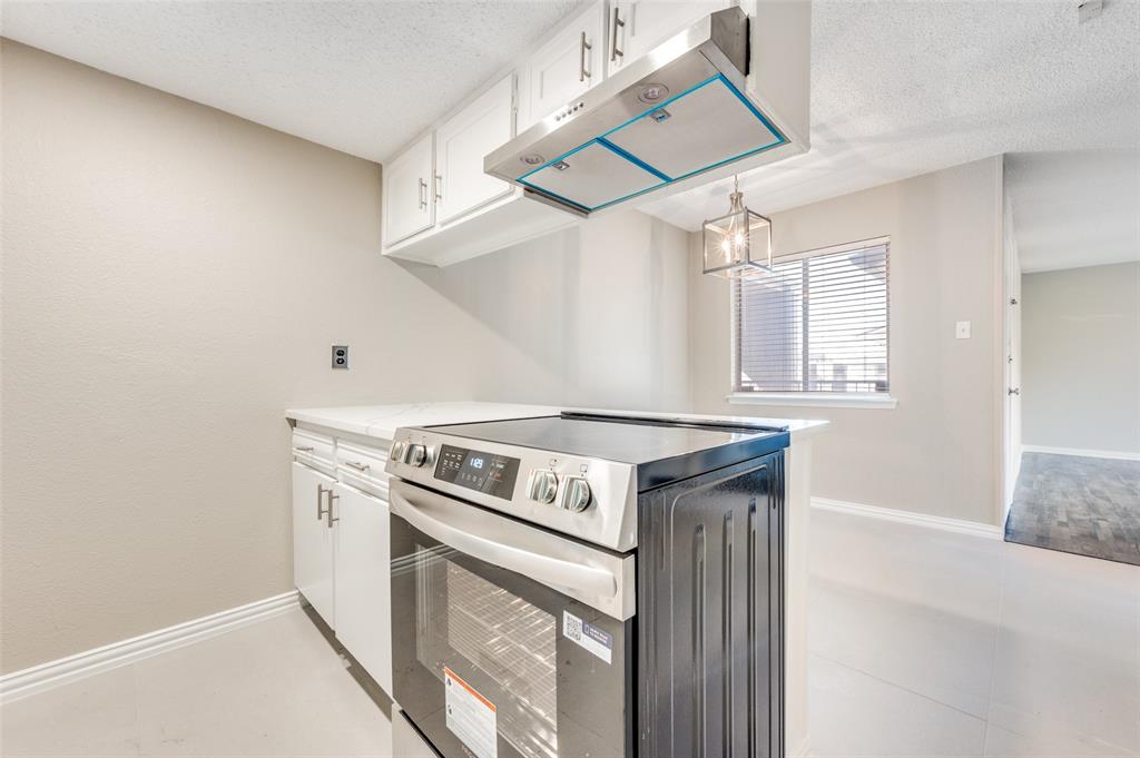Kitchen featuring white cabinetry, stainless steel range, mounted stainless steel range hood, and a pendant light fixture
