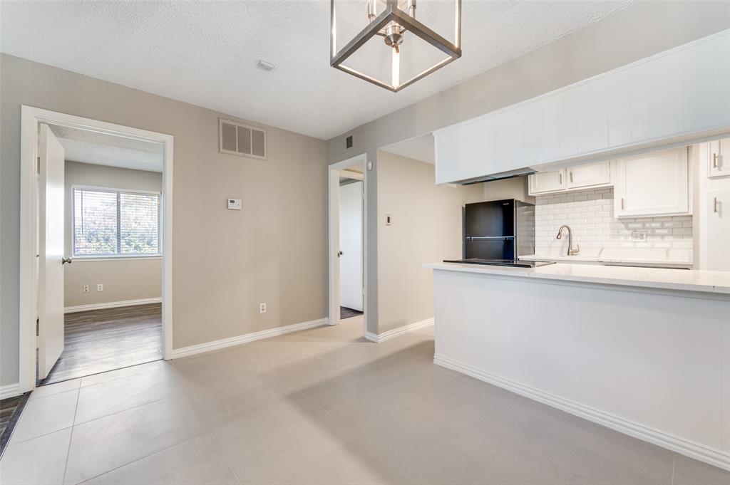 Kitchen featuring white cabinetry, subway tile backsplash, quartz countertops, and geometric lantern-style ceiling lighting, complemented by tile flooring