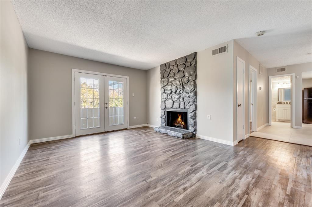 Living space featuring Wood-look luxury vinyl planks (LVP) , and tone-veneer fireplace with raised hearth, and double French doors
