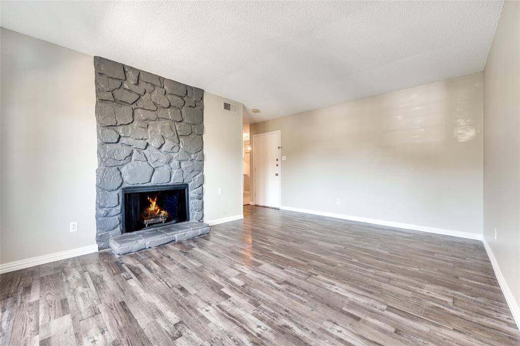 Living area featuring Wood-look luxury vinyl planks (LVP) and a floor-to-ceiling hearth with grey stone masonry and a raised stone hearth