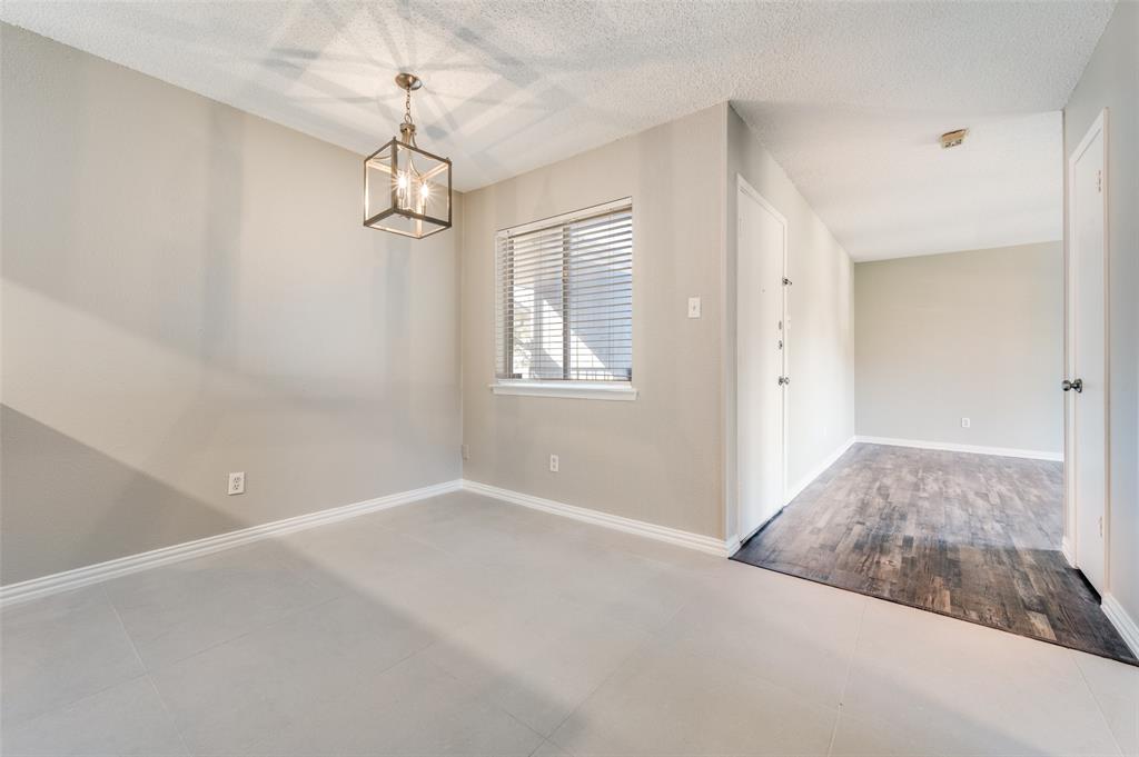 Neutral-toned interior featuring large-format ceramic tile flooring, a geometric metal lantern pendant light, and dark wood-finish flooring