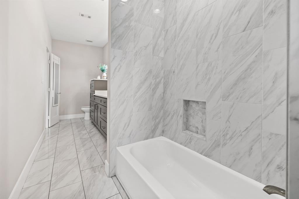 Full bathroom with tile flooring, tiled shower / bath, vanity, and toilet