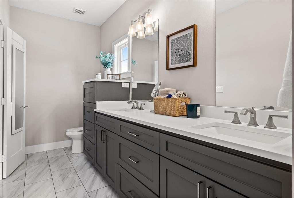 Bathroom featuring dual vanity, tile flooring, and toilet