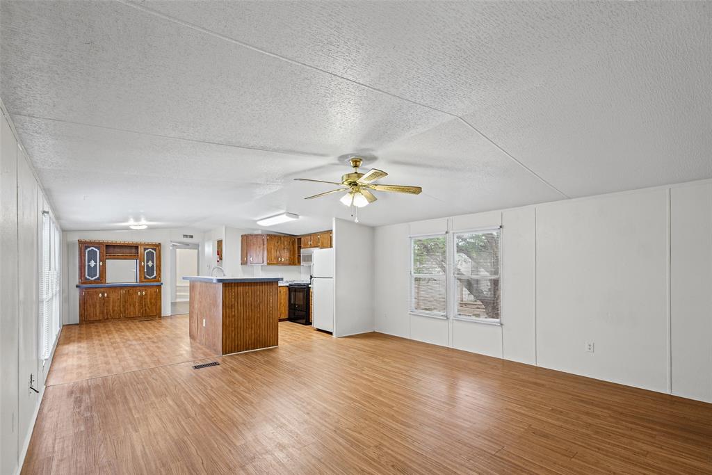 Open-concept area featuring wood-finish flooring, a kitchen island, built-in cabinetry, and a ceiling-mounted light fixture