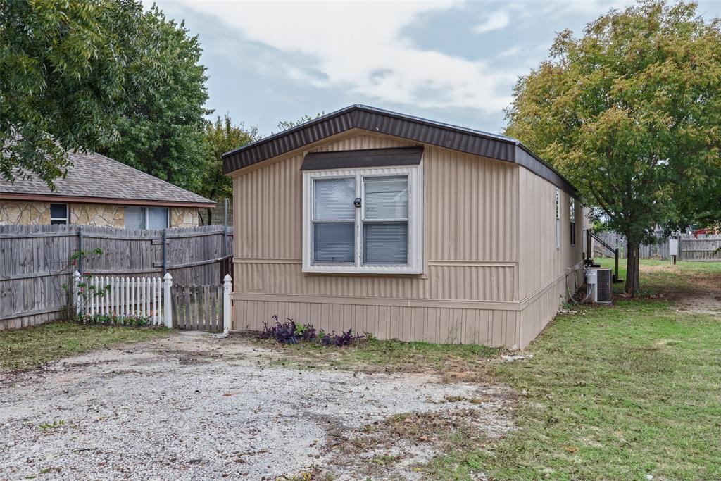 Exterior featuring corrugated metal siding, a gabled roofline, double-pane windows, and a gravel driveway