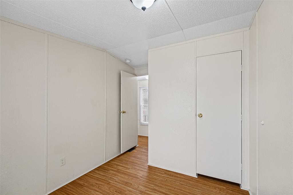 Interior room featuring wood-finish flooring, smooth-panel walls, a ceiling-mounted light fixture, and a white interior door