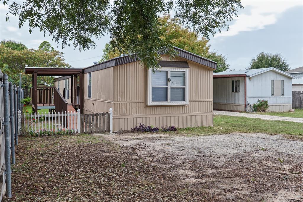 Exterior features include a metal-sided facade, a covered porch, a white picket fence, and a gravel driveway