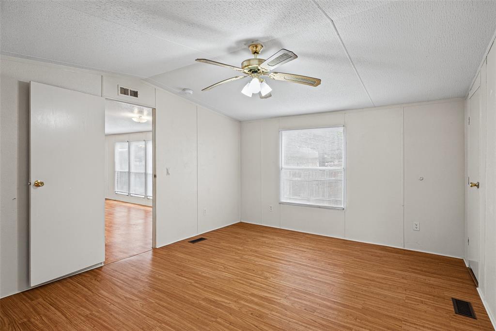 Interior room featuring wood-finish flooring, a ceiling fan with integrated lighting, and a single-pane window