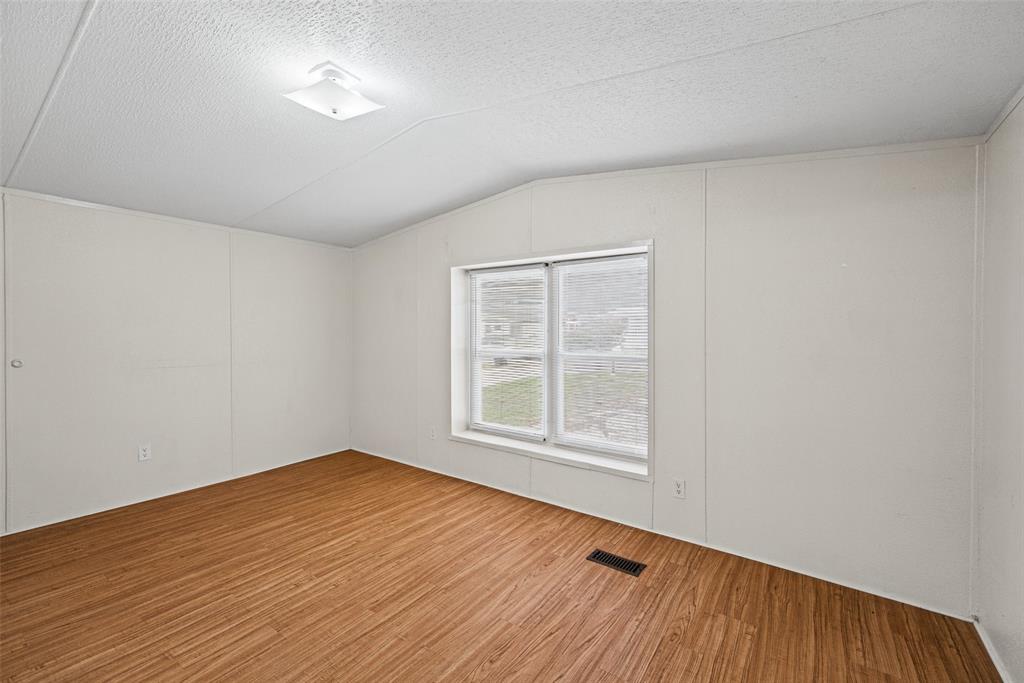 Interior room featuring wood-finish flooring, vaulted ceilings, a central flush-mount light fixture, and a dual-pane window