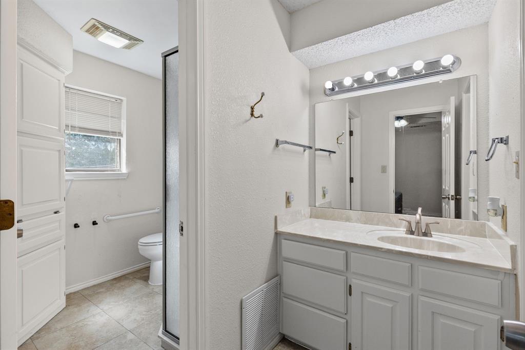 Bathroom featuring a vanity with white cabinetry, a single-basin sink, a multi-bulb vanity light, and large-format tile flooring