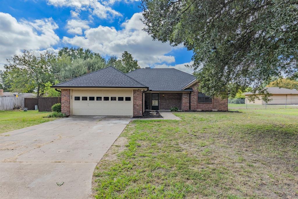 Single-story brick exterior featuring a hipped roof, attached two-car garage with overhead door, and concrete driveway Single-story brick exterior featuring a hipped roof, attached two-car garage with overhead door, and concrete driveway