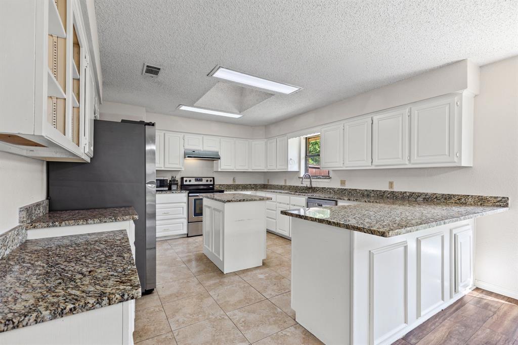 Kitchen featuring white shaker-style cabinetry, stone-finish countertops, a center island, recessed lighting, and tile flooring