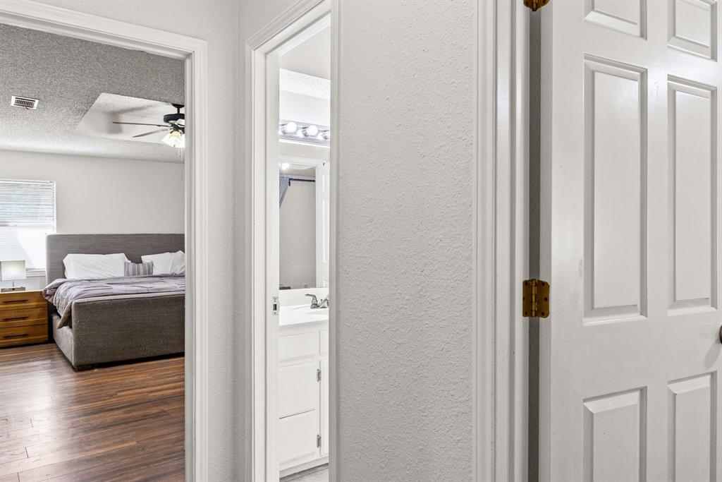 White six-panel interior doors, wood-finish flooring, and white vanity cabinetry with a rectangular basin