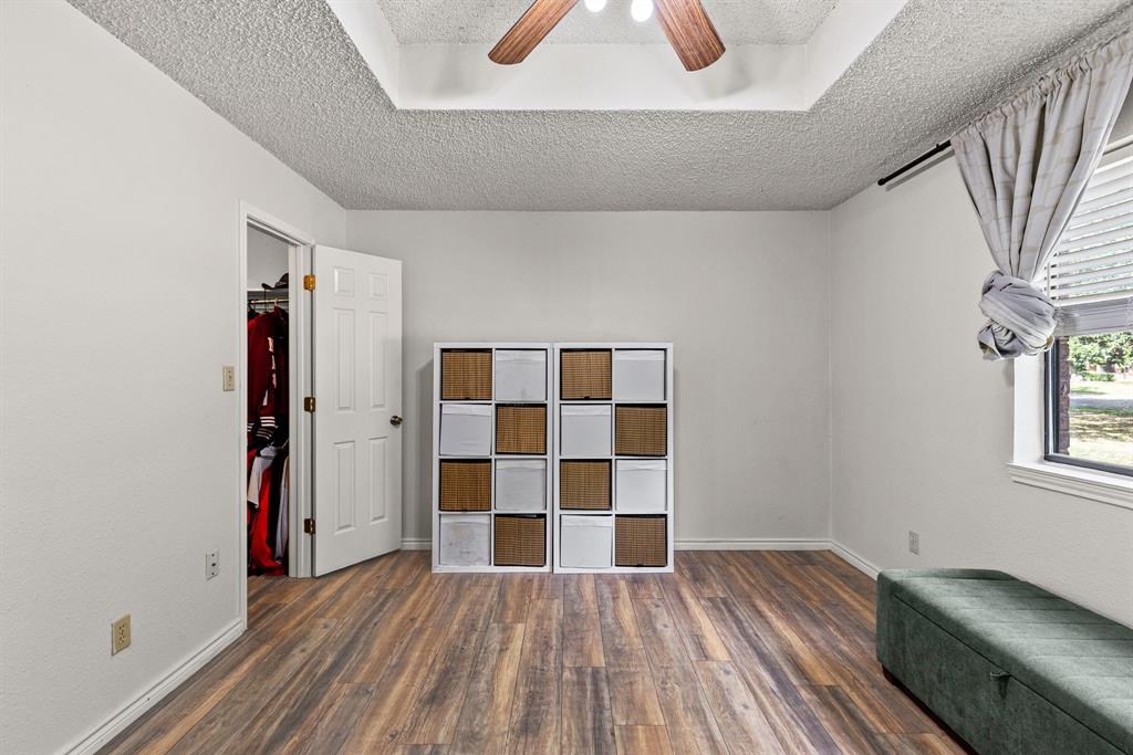 Interior space featuring wood-finish flooring, tray ceiling, and a ceiling fan