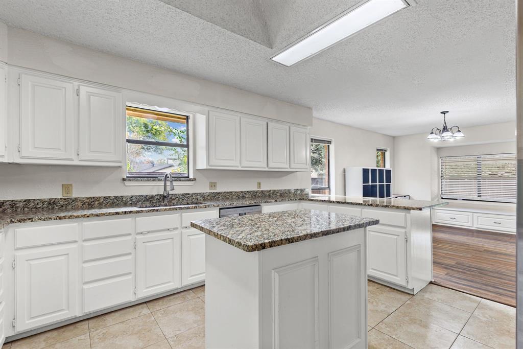 Kitchen featuring stone countertops, white shaker-style cabinetry, a central island, recessed ceiling lighting, and tile flooring