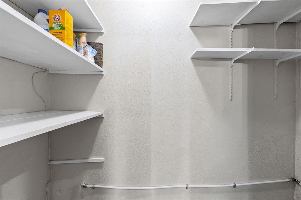 Storage space featuring white adjustable shelving units mounted on metal tracks
