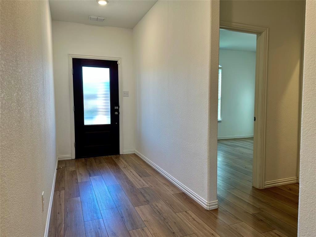 Entryway featuring wood-finish flooring, a solid black front door with a vertical frosted glass panel, and recessed ceiling lighting