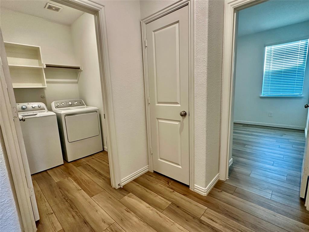 Laundry area featuring wood-finish flooring, built-in shelving, and a paneled interior door