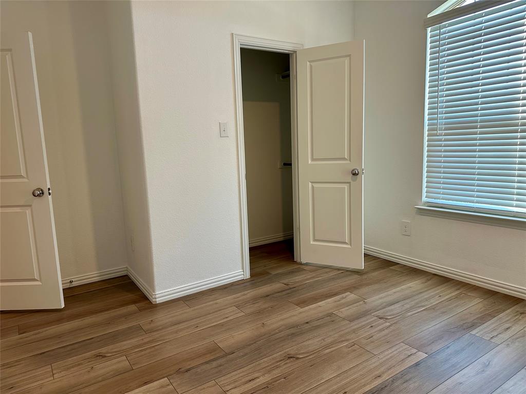 Wood-finish flooring, two-panel interior doors, and a window with horizontal blinds