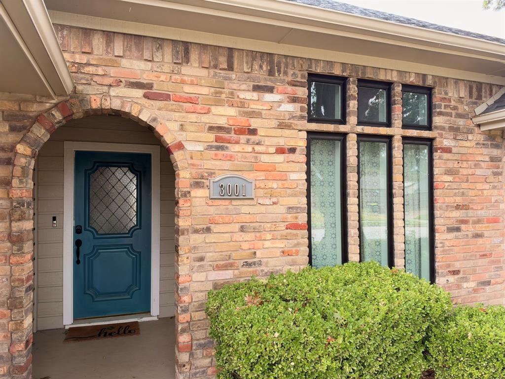 Exterior featuring a multi-tonal brick facade, arched entryway, solid door with leaded-glass inset, and a triple-pane window arrangement with black framing Exterior featuring a multi-tonal brick facade, arched entryway, solid door with leaded-glass inset, and a triple-pane window arrangement with black framing