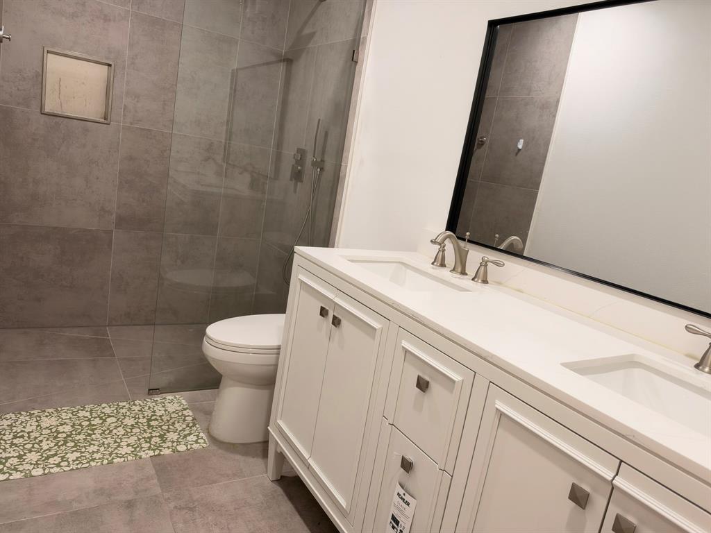 Double vanity with white cabinetry, quartz countertop, and integrated dual sinks featuring metallic fixtures Double vanity with white cabinetry, quartz countertop, and integrated dual sinks featuring metallic fixtures