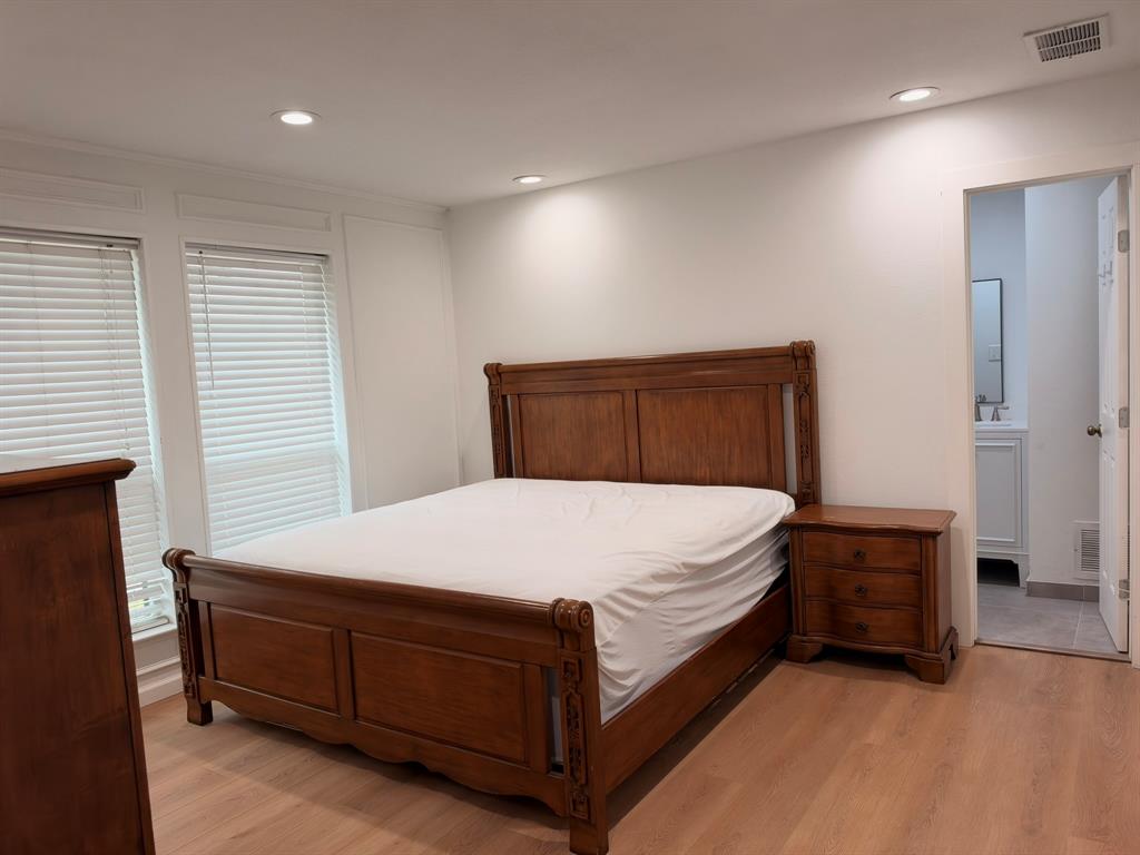 Neutral-toned interior featuring wood-finish flooring, recessed lighting, double windows with horizontal blinds, and paneled wall detailing Neutral-toned interior featuring wood-finish flooring, recessed lighting, double windows with horizontal blinds, and paneled wall detailing