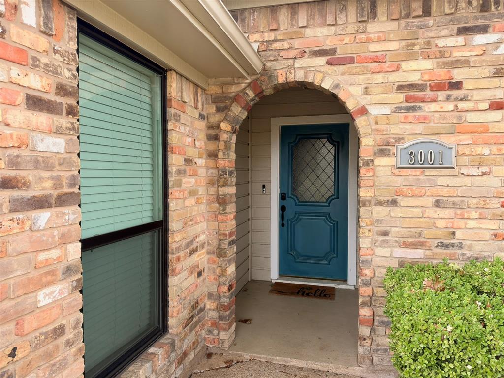 Multi-colored brick exterior featuring an arched entryway, recessed porch, decorative paneled front door with diamond-patterned glass, and custom house number plaque Multi-colored brick exterior featuring an arched entryway, recessed porch, decorative paneled front door with diamond-patterned glass, and custom house number plaque