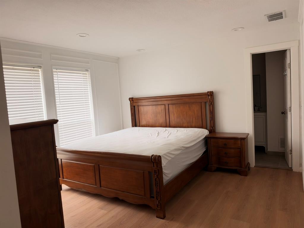Interior room featuring wood-finish flooring, recessed lighting, and crisp white wall paneling with double-window configuration Interior room featuring wood-finish flooring, recessed lighting, and crisp white wall paneling with double-window configuration