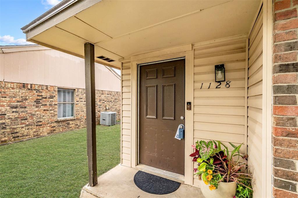 1128 Covered entryway featuring a six-panel door, horizontal siding, brick exterior accents, and an attached exterior light fixture 1128 Covered entryway featuring a six-panel door, horizontal siding, brick exterior accents, and an attached exterior light fixture
