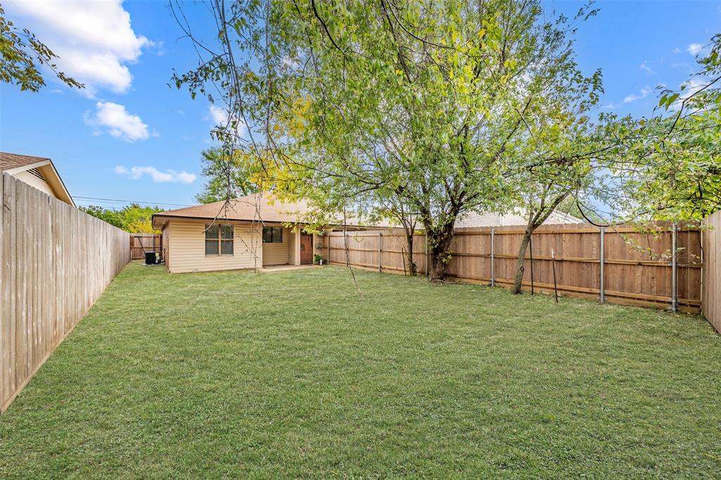 1126 Expansive backyard featuring a grass lawn, full-perimeter wood fencing, and mature trees