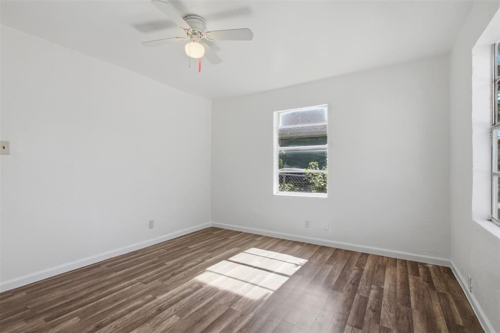 Room featuring wood-finish flooring, white walls, two windows, and a ceiling-mounted fan with integrated light