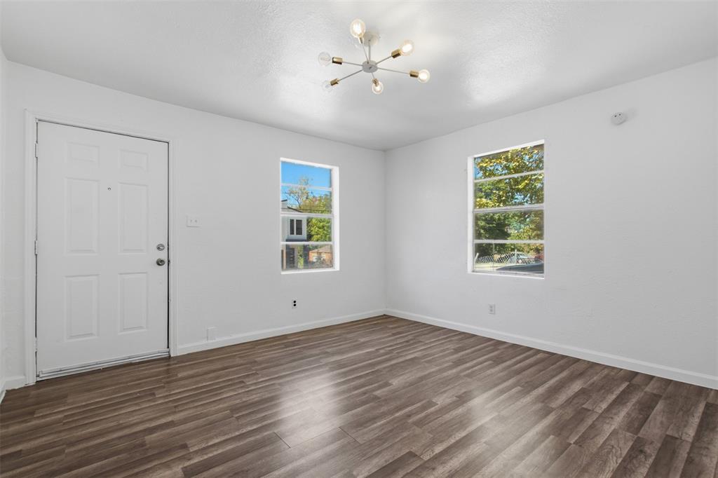 Neutral interior featuring wood-finish flooring, two multi-pane windows, a six-light sputnik-style ceiling fixture, and a white paneled entry door
