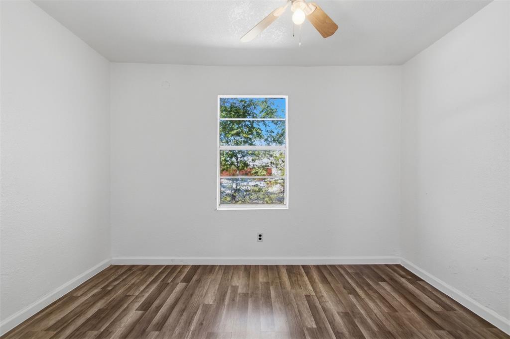 Interior room featuring wood-finish flooring, white walls, and a ceiling-mounted light fixture with a fan