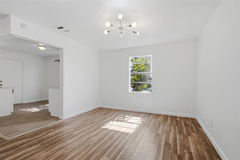 Interior featuring wood-finish flooring, modern multi-arm ceiling light fixture, neutral wall palette, and a single-pane window