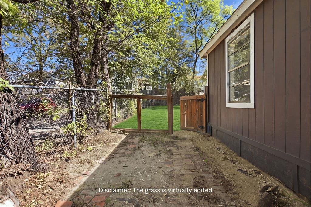 Exterior yard space featuring a brick-paver patio, wood-panel siding, a chain-link fence, and a wooden gate