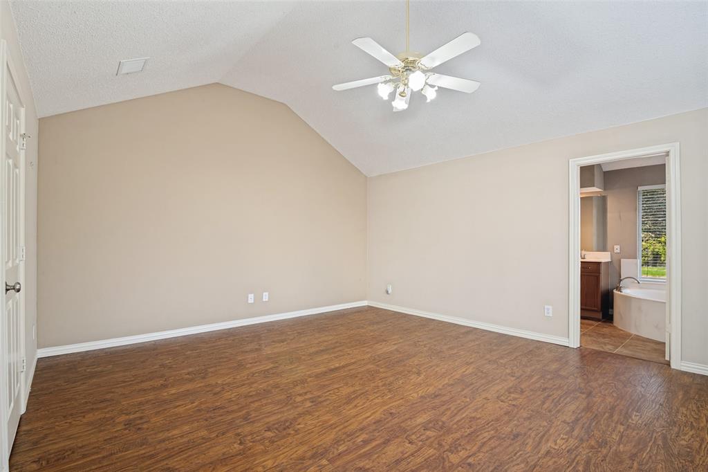Vaulted ceiling featuring a central multi-blade ceiling fan with integrated light fixture and wood-finish flooring