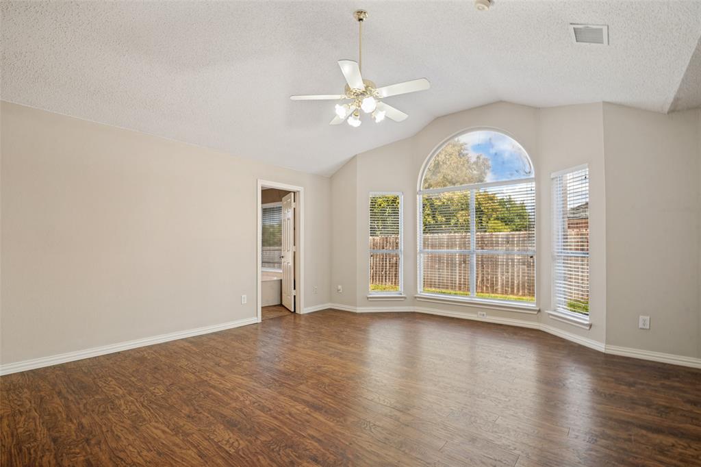 Living area featuring vaulted ceilings, wood-finish flooring, an arched window, and a multi-light ceiling fan