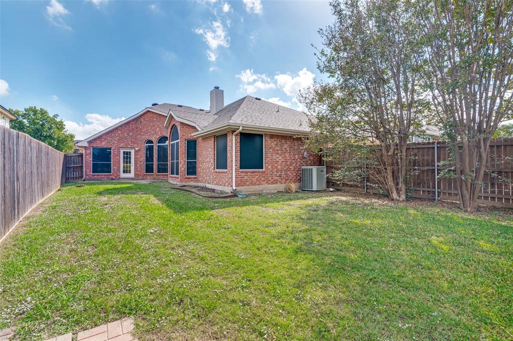 Brick exterior featuring arched windows, a hipped roofline, and an expansive fenced backyard with mature trees