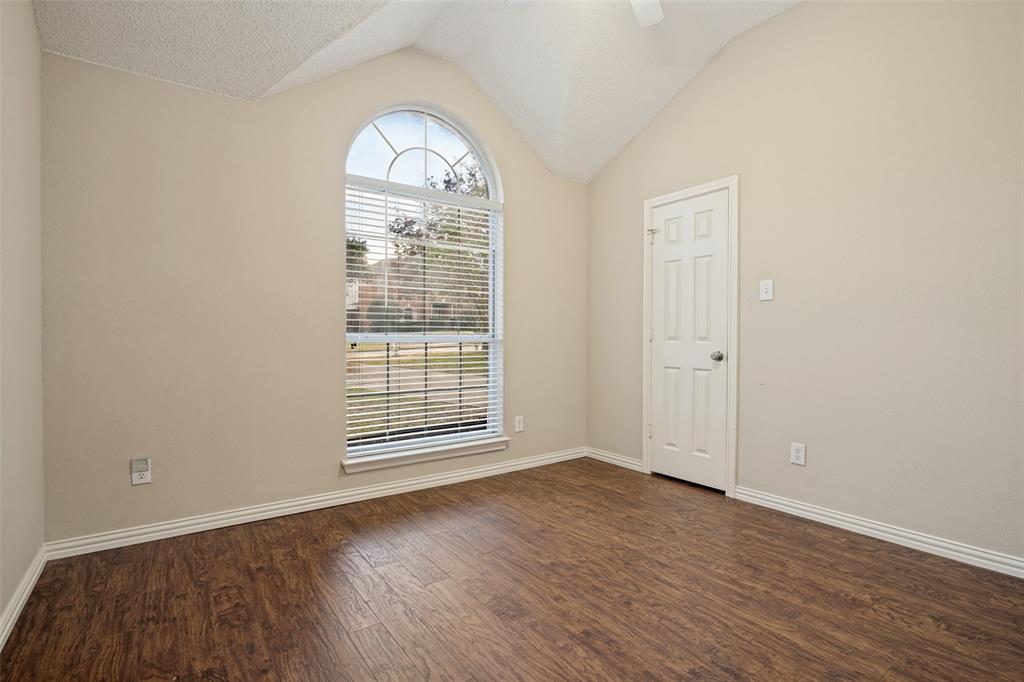 Vaulted ceilings featuring an arched window, wood-finish flooring, and a six-panel door