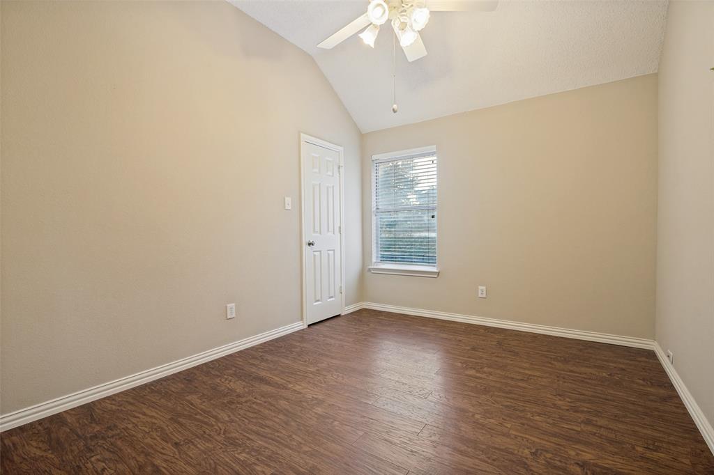 Room featuring vaulted ceilings, wood-finish flooring, a ceiling fan with integrated lighting, and a single-panel interior door