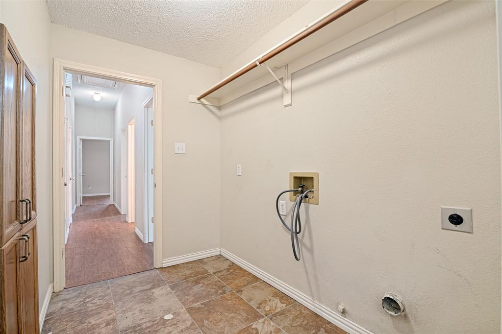 Utility area featuring tile flooring, built-in wooden cabinetry, and overhead shelving with a hanging rod