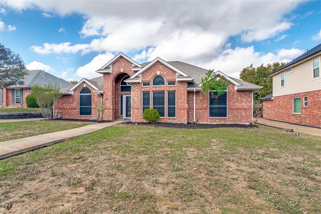 Brick exterior featuring a gabled roofline, arched window detailing, and a prominent covered entryway