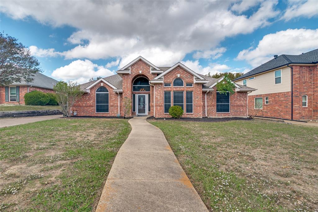Brick exterior featuring a gabled roofline, arched entryway, multi-paned windows, and a concrete walkway Brick exterior featuring a gabled roofline, arched entryway, multi-paned windows, and a concrete walkway