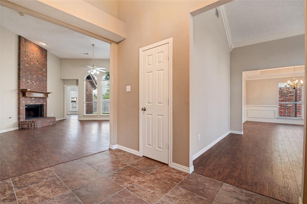 Foyer featuring tile flooring, vaulted ceilings, and a floor-to-ceiling brick fireplace with a wood mantel Foyer featuring tile flooring, vaulted ceilings, and a floor-to-ceiling brick fireplace with a wood mantel