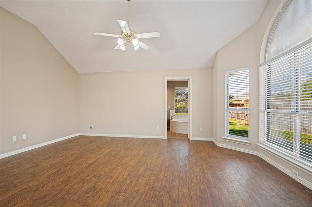Vaulted ceilings, wood-finish flooring, arch-top windows, and a multi-light ceiling fan